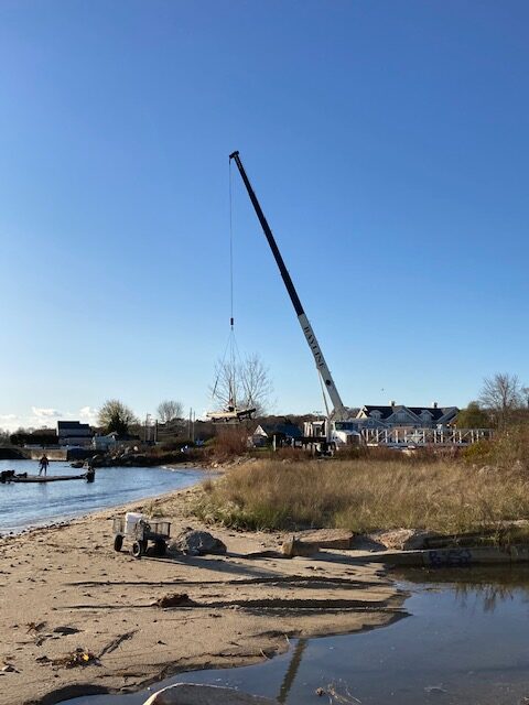 Crane hoisting float from water to the beach