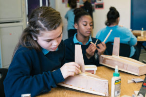 Students gluing keels on model boats